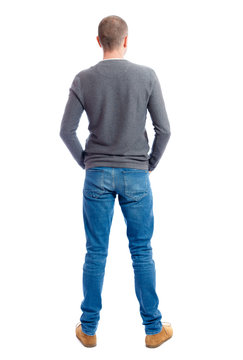 Back view of man in jeans. Standing young guy. Rear view people collection.  backside view of person.  Isolated over white background.  A guy in a gray sweater standing with folded hands in his