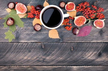 Coffee cup, autumn leaves and dried rowan on wooden background. Autumn card. Lots of copy space. Top view