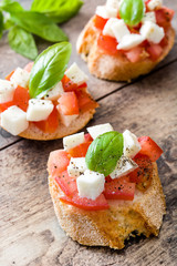 Caprese salad bruschetta with tomatoes,mozzarella and basil on wooden table


