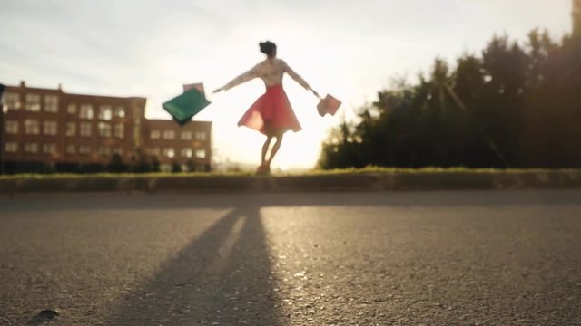 Blurred Shopaholic woman in beautiful dress holding many shopping bags walking on the street through the sun during sunset in slowmotion. 1920x1080