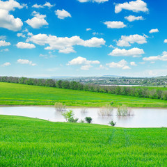 green field, lake and cloudy sky