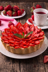 Tart with strawberries and whipped cream on wooden vintage table