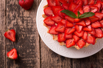 Tart with strawberries and whipped cream on wooden vintage table