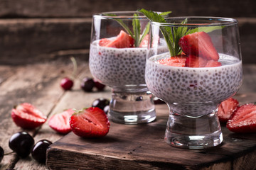 chia seed pudding with strawberries and min on wooden vintage background