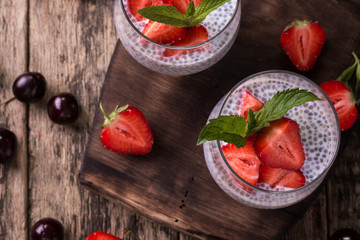 chia seed pudding with strawberries and min on wooden vintage background