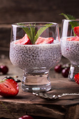 chia seed pudding with strawberries and min on wooden vintage background
