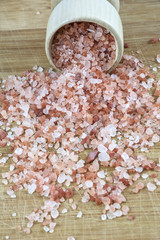 Pink salt in the wooden bowl on the wooden background