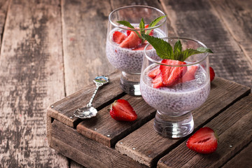 chia seed pudding with strawberries and min on wooden vintage background