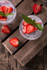 chia seed pudding with strawberries and min on wooden vintage background