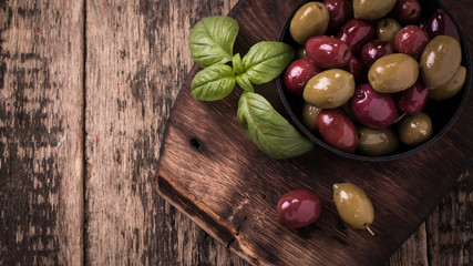 Olives on wooden dark table with basil