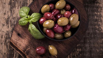Olives on wooden dark table with basil