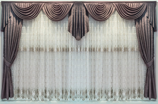 Interior decoration in a classic style. Brown curtains with the pelmet and a delicate tulle.