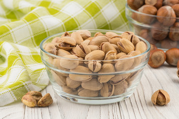 Pistachios in a glass bowl on the old wooden table.