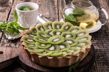 Tart with kiwi and whipped cream on wooden vintage table