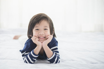 asian child lying on white bed