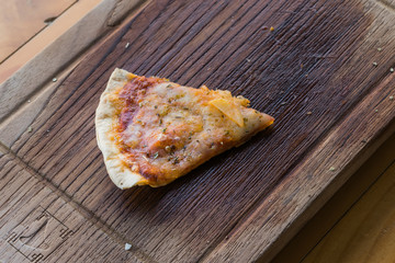 One piece of pizza on wood board