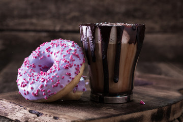 donuts and a cup of coffee with chocolate on a wooden table