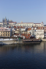 Fototapeta na wymiar Snowy Prague gothic Castle above river Vltava in the sunny Day, Czech Republic