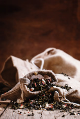 Dry green tea with flower petals in canvas bags, vintage wood ba