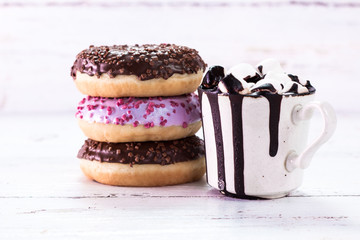 donuts and a cup of coffee with chocolate on a wooden table