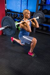Fototapeta na wymiar Determined man lifting barbell in fitness studio