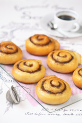 Cinnamon Rolls on transparent board and light pink napkin, on white background.