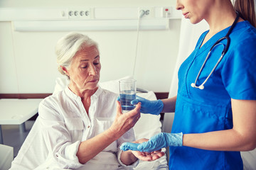 Fototapeta na wymiar nurse giving medicine to senior woman at hospital