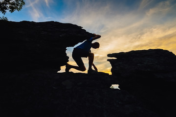 Young man climbing on top of rock mountain