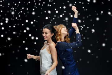 happy young women dancing over snow