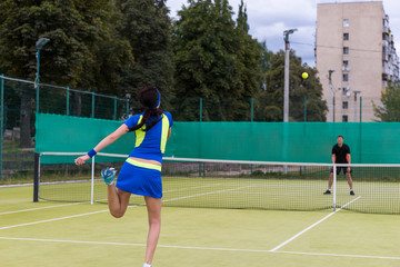 Obraz premium View from the back on a young female tennis player serving durin
