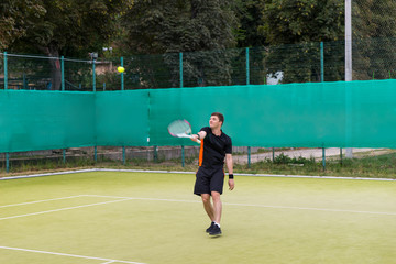 Fototapeta premium Confident young man in sports clothes playing tennis