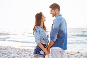 Couple standing and holding hands on the beach