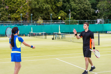 Male tennis player throws the ball to his female partner after a
