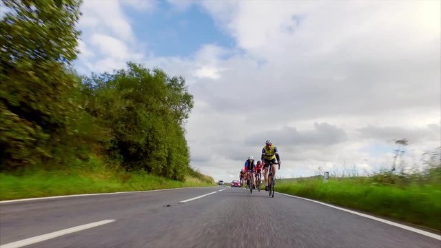 A stabilised cam of a group of cycling athletes out on a training ride on country roads in the UK countryside on a sunny day. 