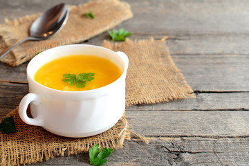 Easy pumpkin soup. Vegetable soup with rice and potatoes in a bowl, spoon, old wooden background. Vintage style