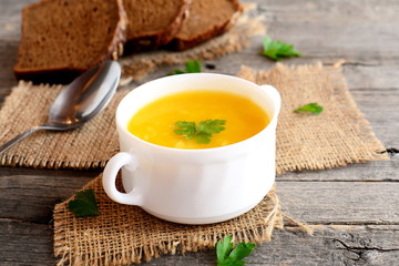 Pumpkin soup with potatoes and rice. Pumpkin soup in a bowl, spoon, bread slices on old wooden background. Vegetarian recipe. Closeup
