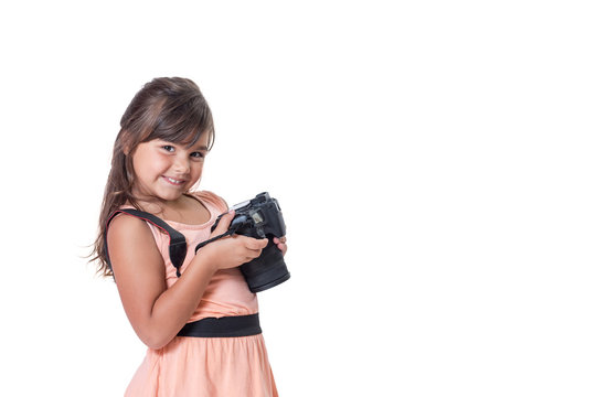 Smiling long hair little girl is holding SLR camera. The girl is slightly skewed and is looking at the camera. All is isolated on the white background. All potential trademarks are removed.