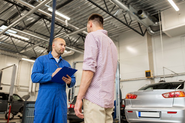 Fototapeta premium auto mechanic with clipboard and man at car shop
