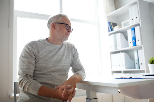 Senior Man Sitting At Medical Office Table