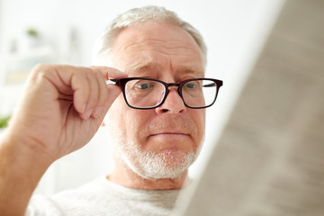 close up of old man in glasses reading newspaper 