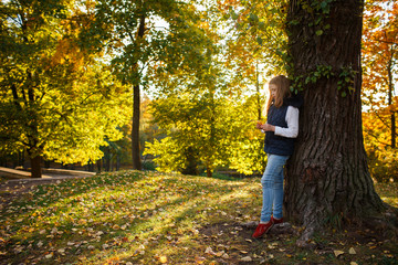 Cute Teenager girl walks in Autumn park. Sunny day, selective focus