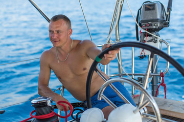 Man skipper relaxed runs his sailing yaht boat.