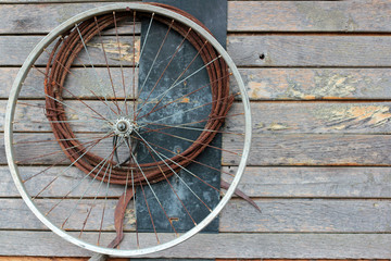 Fototapeta na wymiar Old bike wheel and a rusty cable on a wooden wall