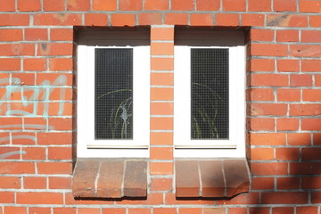 Schmale Kunststoffenster an Backsteinwand