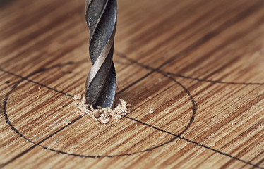 Old iron drill bit makes a hole in a wood