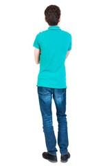 Back view of man in jeans. Standing young guy. Rear view people collection.  backside view of person.  Isolated over white background. A guy in a T-shirt is stylish aquamarine arms folded.