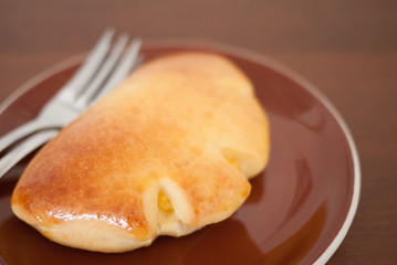 baked bun stuff with sweet cream in dark brown dish