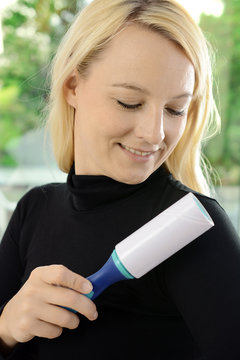 Frau entfernt Flusen mit Fusselrolle von Pullover