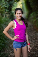 Beautiful woman standing with hand on hip in forest