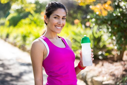 Smiling jogger drinking water while taking a break